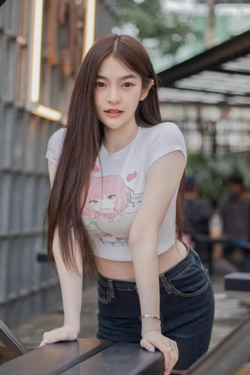 나무 난간에 기대 선 흰 티셔츠와 청바지 차림의 여성